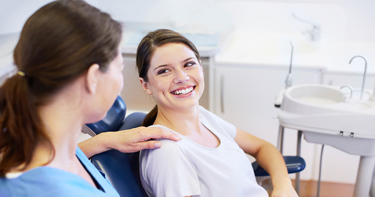 Tandplejer beroliger en smilende patient i stolen